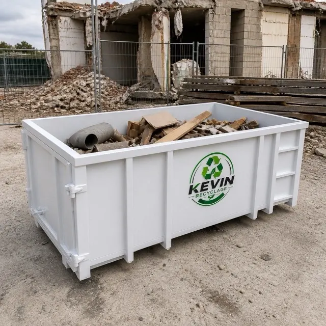 Benne de tout-venant remplie de bois, cartons et gravats devant un bâtiment en démolition