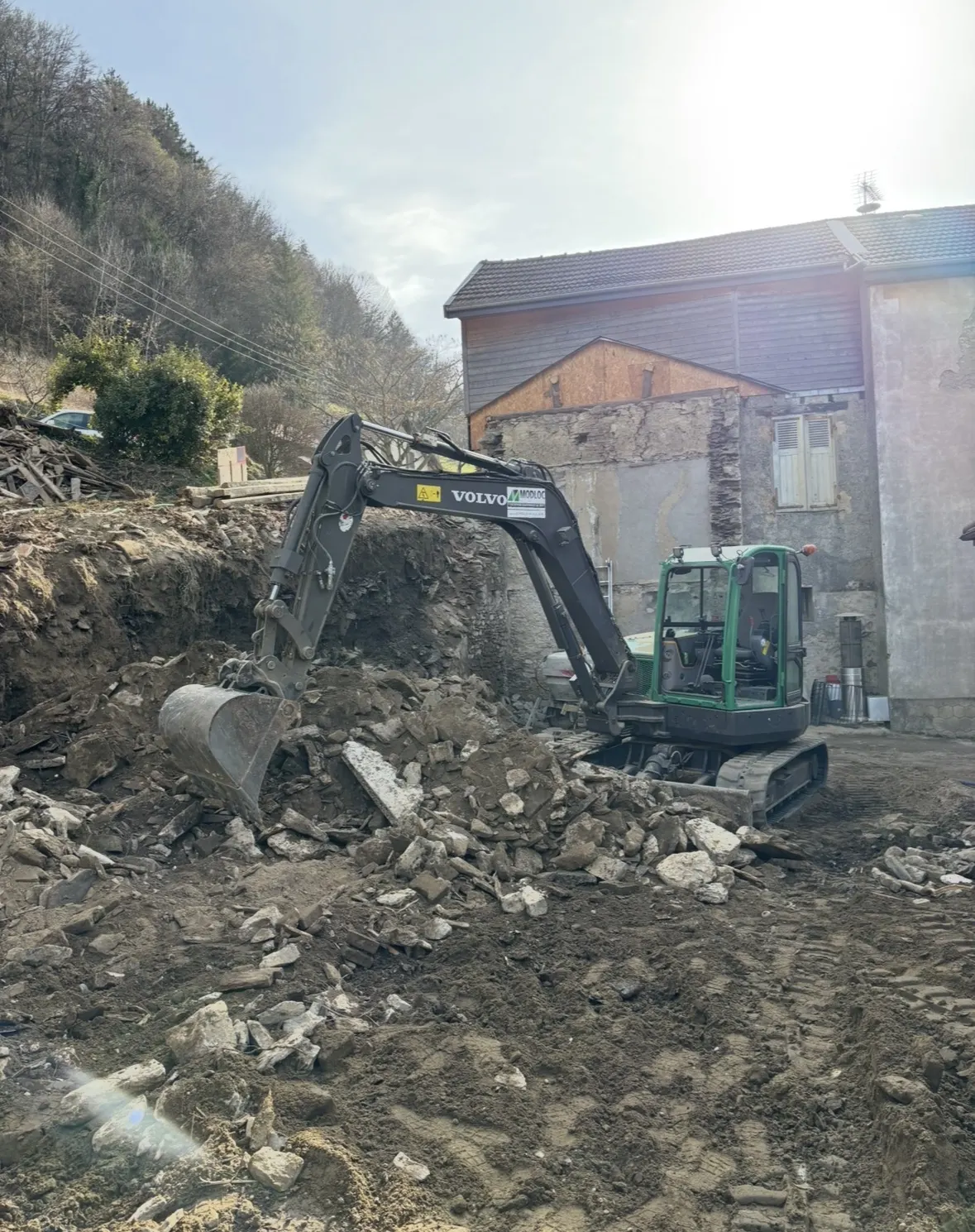 Pelle mécanique reprenant les gravats de béton et de pierre pour évacuation